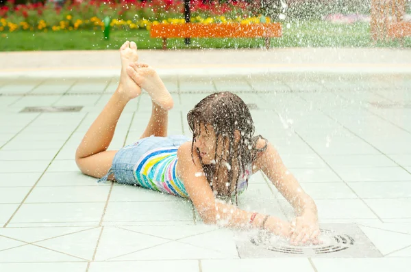 Teenage girl having fun in the water fountain on hot summer day — Stock Photo, Image