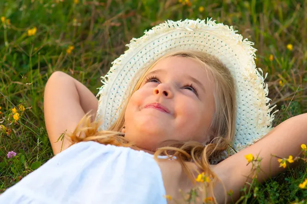 Linda niña tendida en el prado y soñando despierto en hermoso día de verano — Foto de Stock