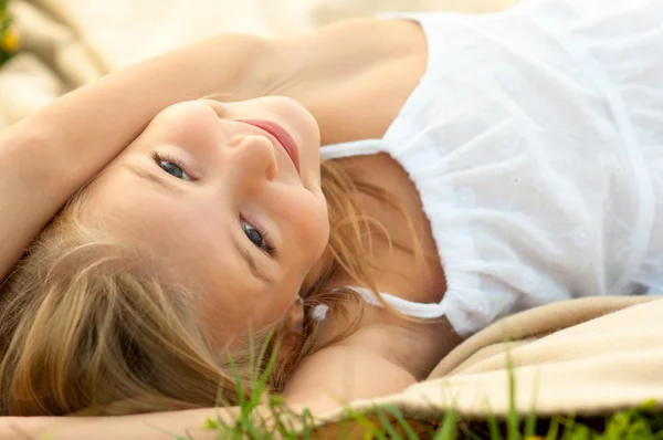 Söt glad liten flicka i vit klänning ligger på filten på vacker sommardag — Stockfoto