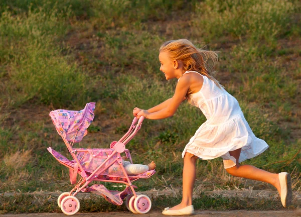 日当たりの良い夏の日に牧草地で彼女の赤ちゃんのおもちゃで遊ぶかわいい女の子 — ストック写真