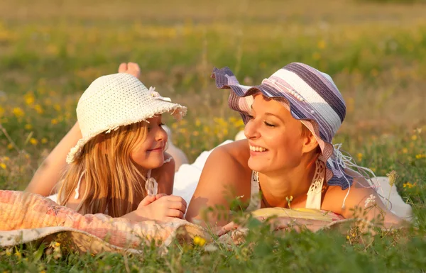 Anne ve kızı çayır on güneşli yaz gününde yalan söylüyor. — Stok fotoğraf