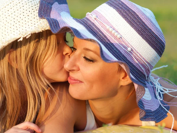 Bonito filhinha beijando sua mãe na bochecha no dia ensolarado de verão — Fotografia de Stock