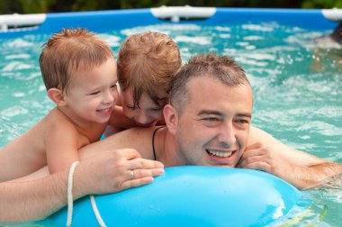 Baba ve çocukları eğlenmek yüzme havuzunda güzel bir yaz gününde