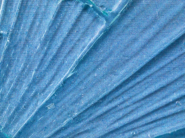 Knäckt glas makro med en himmelsblå mönstrad bakgrund — Stockfoto
