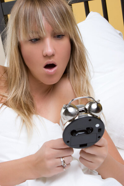 Женщина держит будильник
