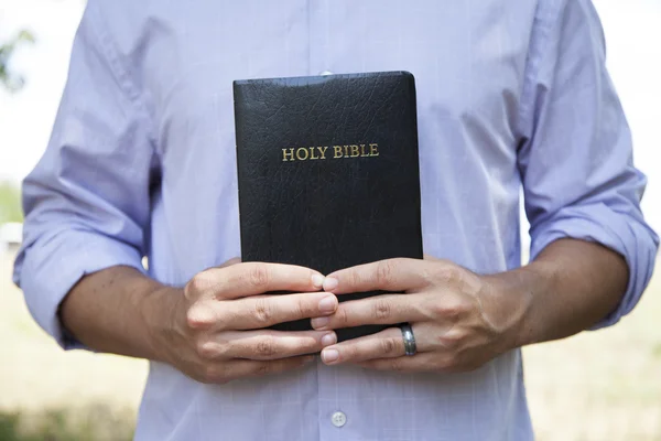 Hombre sosteniendo la Biblia negra — Foto de Stock