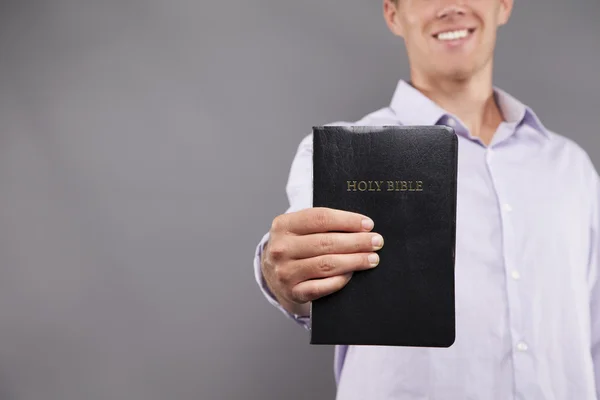 Mosolygó fiatal ember tartja a Biblia — Stock Fotó