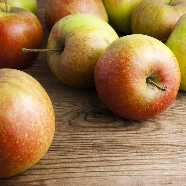Červená jablka na dřevěném stole — Stock fotografie