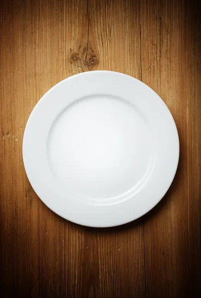 Пустая белая тарелка на деревянном столе — стоковое фото