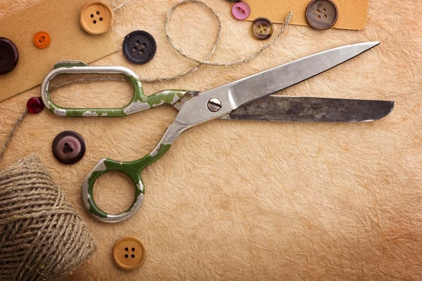 Old scissors and buttons on the paper texture — Stockfoto