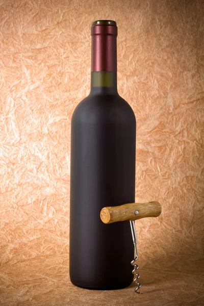 Vinflaska och korkskruv på papper bakgrund — Stockfoto
