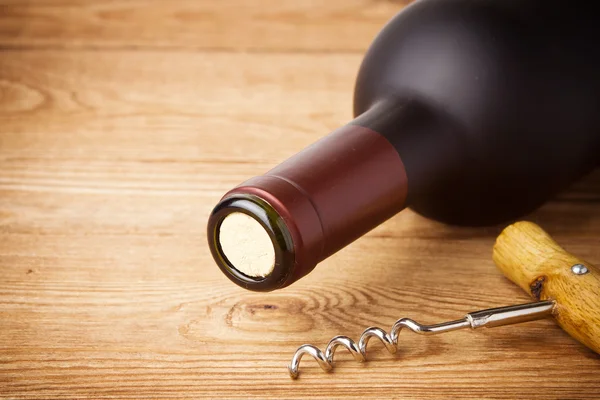 Sacacorchos y botella de vino en el tablero — Foto de Stock