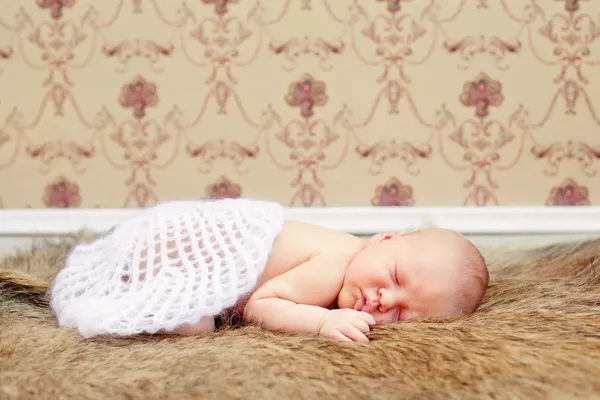 Pasgeboren babyjongen in slaap op een bont deken. — Stockfoto