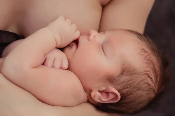 Breast-feeding a newborn baby. The kid in its mother's breast — Stock Photo, Image