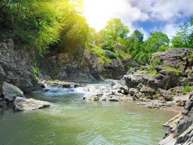 Tranquil waterfall with rocks by a summer clipart