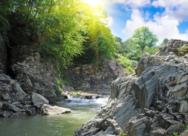 Tranquil waterfall with rocks by a summer clipart