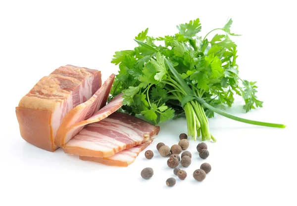 Pieces of bacon are with the bunch of green parsley and by grains of pepper on a white background — Stock Photo, Image