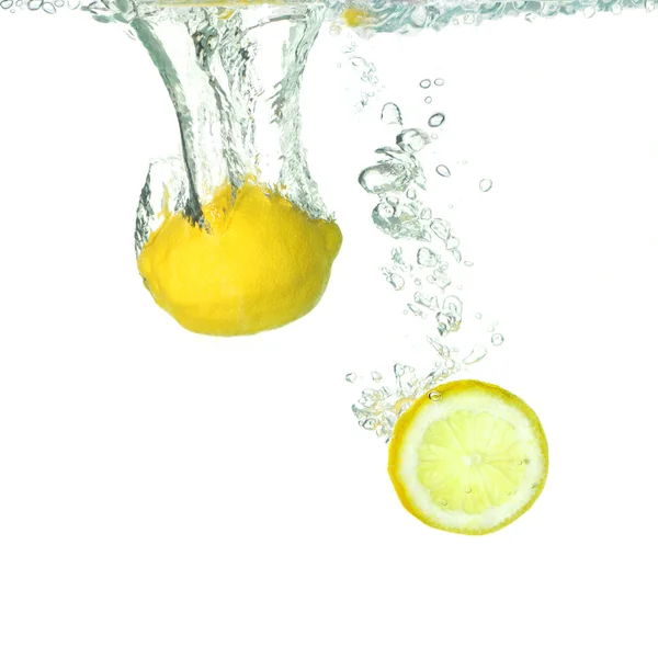 柠檬和落在水中的切片柠檬 — 图库照片