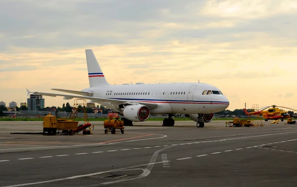 A passenger airliner in the parking lot on the platform of the International Sochi airport at sunset — Stock Photo, Image