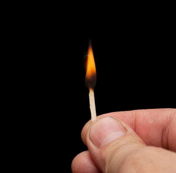 Jogo em chamas na mão sobre um fundo preto — Fotografia de Stock