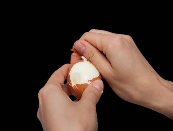 Чистка рук вареное яйцо на черном фоне — стоковое фото