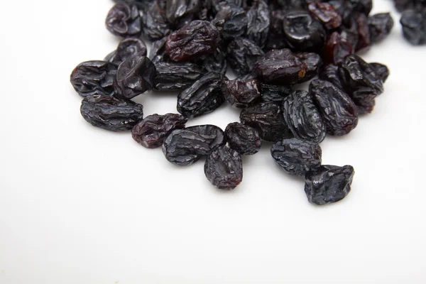 Beyaz zemin üzerine siyah kuru üzüm — Stok fotoğraf
