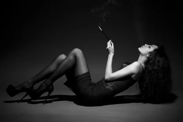 Woman smokes in the dark. studio shot. space for text. BW Image — Stock Photo, Image