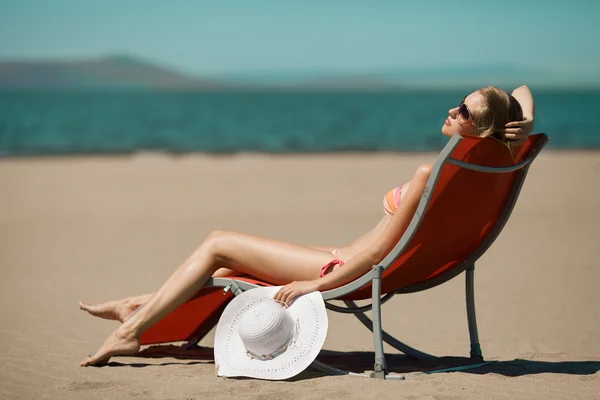 Mooie vrouw liggend op een strandstoel op het strand — Stockfoto