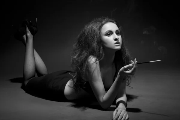 Žena kouří v temnotách. Studio záběr. ČB obraz — Stock fotografie
