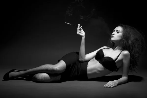 La mujer fuma en la oscuridad. Grabado en estudio. espacio para el texto. Imagen de BW — Foto de Stock