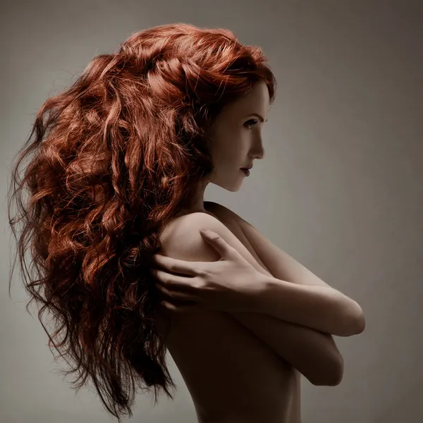 Güzel bir kadın olan gri bir arka plana dayanır kıvırcık saç modeli Telifsiz Stok Imajlar