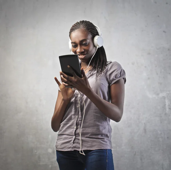 Mujer joven africana sonriente usando una tableta — Foto de Stock