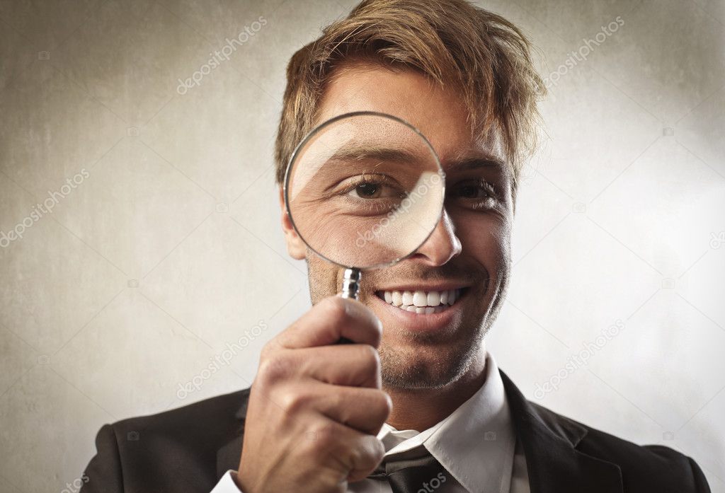 Young businessman looking through a magnifying glass