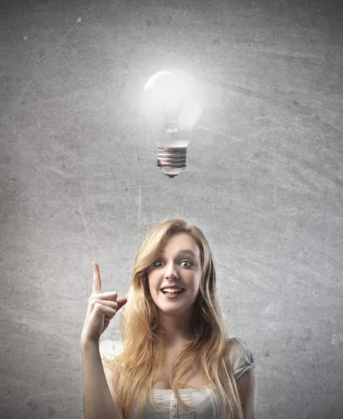 彼女の頭の上に電球を持つという考えを持つ若い女性の笑みを浮かべてください。 — ストック写真