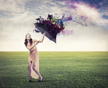 Laughing beautiful woman on a green meadow sheltering from the rainbow under an umbrella clipart