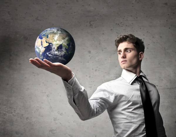 Молодой бизнесмен держит Землю в своих руках [Элементы этого изображения предоставлены НАСА] — стоковое фото