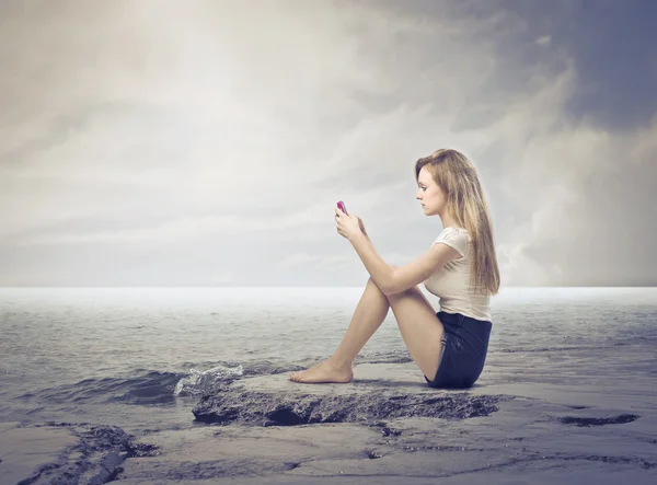Сидячая молодая женщина с помощью мобильного телефона — стоковое фото