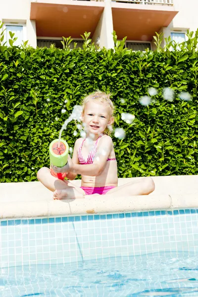 Liten flicka med vatten spruta av poolen — Stockfoto