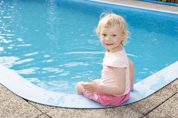スイミング プールのそばで座っている小さな女の子 — ストック写真