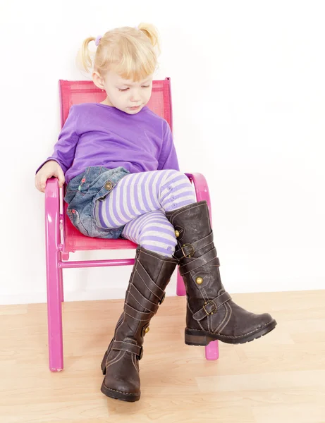 Niña usando botas sentada en la silla — Foto de Stock