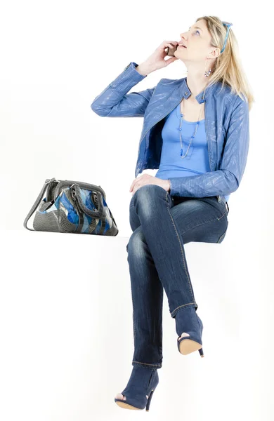 Сидящая женщина с мобильным телефоном и сумочкой — стоковое фото