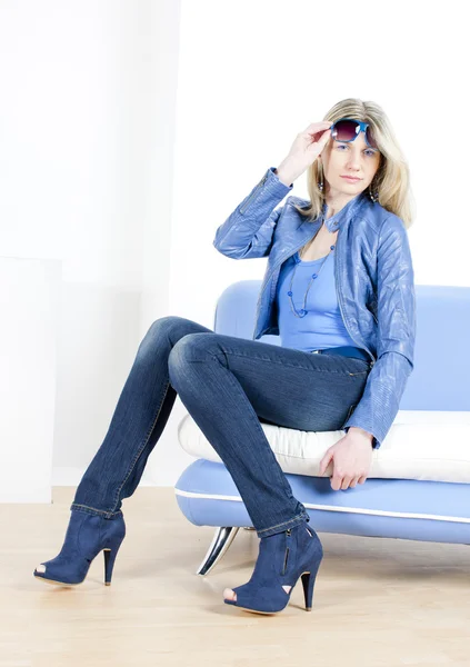 Frau in blauer Kleidung sitzt auf Sofa — Stockfoto