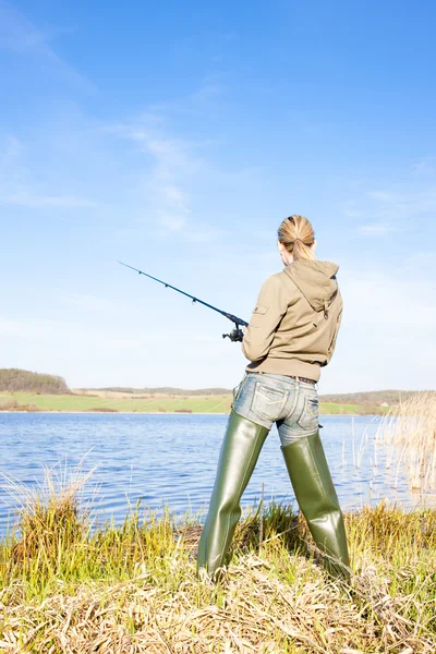Женщина рыбачит у пруда — стоковое фото