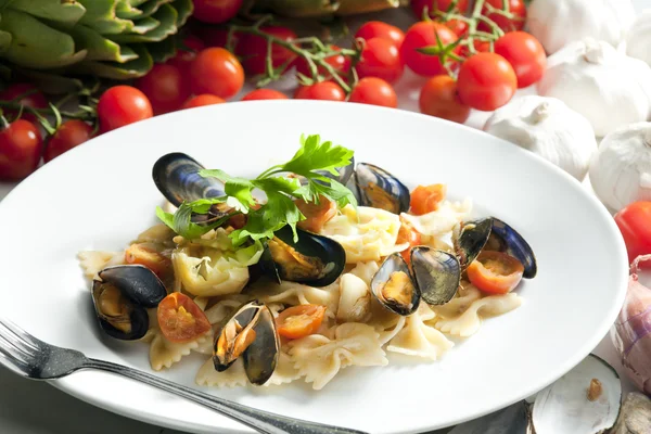 Pasta with mussels, artichokes and cherry tomatoes — Stock Photo, Image