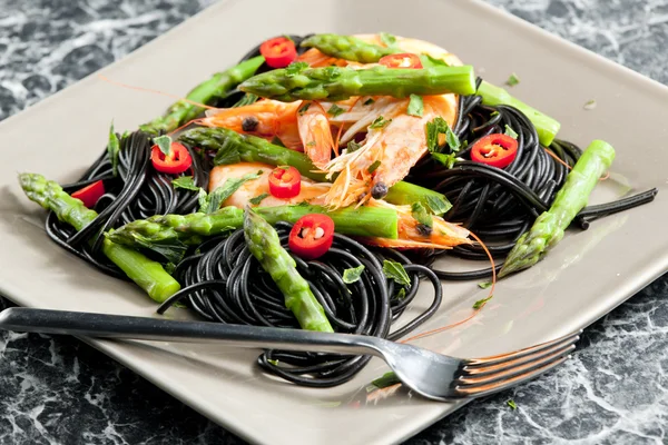 Sepia spaghetti with prawns, asparagus and chilli — Stock Photo, Image