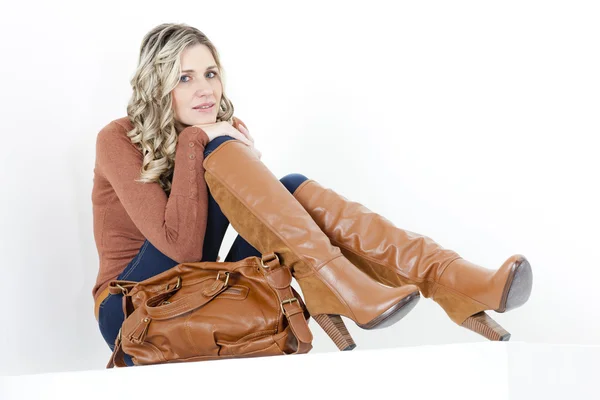 Ülő nő visel divatos csizma barna egy kézitáska — Stock Fotó