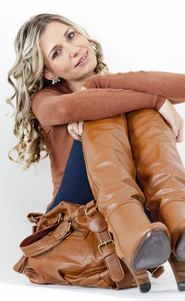 Ritratto di donna seduta che indossa stivali marroni alla moda con una borsa — Foto Stock