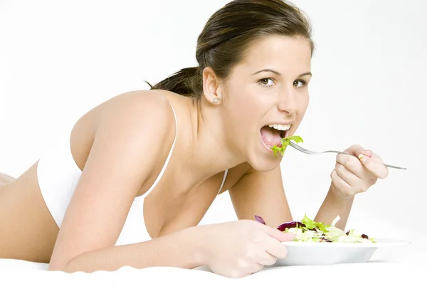 Portrait de femme allongée mangeant de la salade — Photo