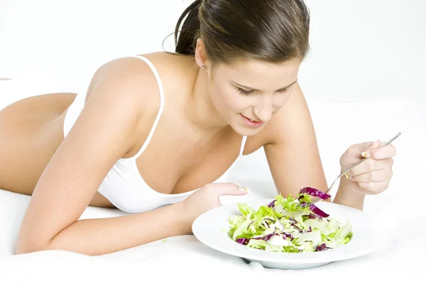 Лежачи жінка їсть салат — стокове фото