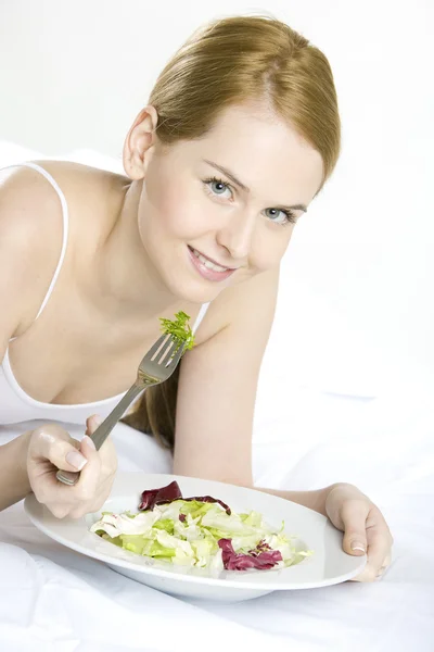 Retrato de mulher deitada comendo salada — Fotografia de Stock